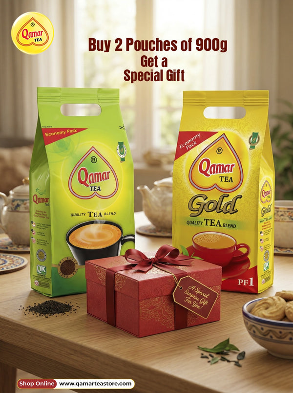 Two Qamar Tea packages, one green and one yellow, with a gift box on a table.
